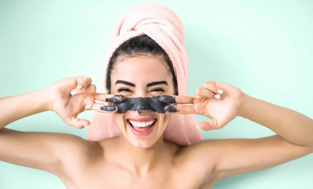 Happy smiling girl applying facial charcoal